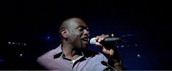 Movie still from “The Sum of All Fears” (2002), directed by Phil Alden Robinson – A man singing into a microphone on a stage; Close Up shot, Low angle