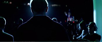 Movie still from “The Sum of All Fears” (2002), directed by Phil Alden Robinson – A man in a suit is standing in a dark room; Medium shot, Low angle
