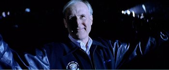 Movie still from “The Sum of All Fears” (2002), directed by Phil Alden Robinson – An older man in a jacket is smiling for the camera; Close Up shot, Low angle