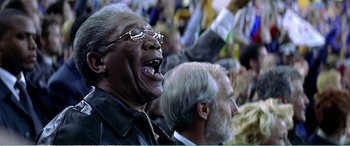 Movie still from “The Sum of All Fears” (2002), directed by Phil Alden Robinson – A man with glasses is laughing while sitting next to another man; Close Up shot, Low angle