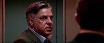 Movie still from “The Sum of All Fears” (2002), directed by Phil Alden Robinson – A person wearing a suit and tie; Close Up shot, Low angle