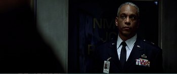 Movie still from “The Sum of All Fears” (2002), directed by Phil Alden Robinson – A man in a suit and tie standing in front of a building; Close Up shot, Low angle