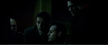 Movie still from “The Sum of All Fears” (2002), directed by Phil Alden Robinson – A group of men standing next to each other in a dark room; Medium shot, Low angle
