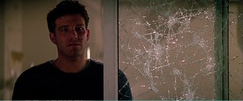 Movie still from “The Sum of All Fears” (2002), directed by Phil Alden Robinson – A man standing in front of a broken glass window; Close Up shot, Low angle