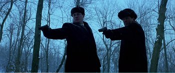 Movie still from “The Sum of All Fears” (2002), directed by Phil Alden Robinson – A man in a black coat and a man in a brown hat and a gun; Medium shot, Low angle