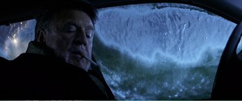 Movie still from “The Sum of All Fears” (2002), directed by Phil Alden Robinson – A man sitting in a car in front of a wave; Close Up shot, Low angle