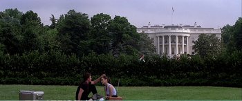 Movie still from “The Sum of All Fears” (2002), directed by Phil Alden Robinson – A man and a woman sitting on the grass near the white house; Extreme Wide shot, Over the shoulder angle