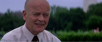 Movie still from “The Sum of All Fears” (2002), directed by Phil Alden Robinson – An older man wearing a white dress shirt and tie; Close Up shot, Over the shoulder angle