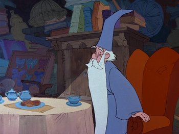 Movie still from “The Sword in the Stone” (1963), directed by Wolfgang Reitherman – An old man with a long white beard is sitting at a table; Medium shot, Over the shoulder angle