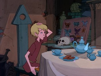 Movie still from “The Sword in the Stone” (1963), directed by Wolfgang Reitherman – A boy is sitting at a table in front of a tea set; Medium shot, High angle
