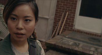 Movie still from “The Taking of Deborah Logan” (2014), directed by Adam Robitel – A young woman with braids standing in front of a brick building; Close Up shot, Over the shoulder angle