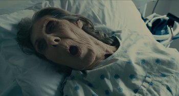 Movie still from “The Taking of Deborah Logan” (2014), directed by Adam Robitel – An old woman laying in bed with a dog face; Close Up shot, High angle