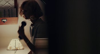 Movie still from “The Taking of Deborah Logan” (2014), directed by Adam Robitel – A woman holding a microphone in a room; Medium shot, Over the shoulder angle