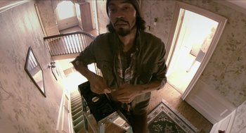 Movie still from “The Taking of Deborah Logan” (2014), directed by Adam Robitel – A man standing in a room holding a video game controller; Medium shot, Low angle