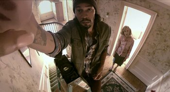 Movie still from “The Taking of Deborah Logan” (2014), directed by Adam Robitel – A man taking a selfie with a woman standing in the background; Medium shot, Overhead angle