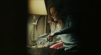 Movie still from “The Taking of Deborah Logan” (2014), directed by Adam Robitel – A woman sitting at a table next to a lamp; Medium shot, High angle