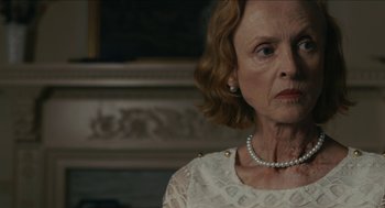 Movie still from “The Taking of Deborah Logan” (2014), directed by Adam Robitel – An older woman wearing a white dress and a pearl necklace; Close Up shot, Over the shoulder angle