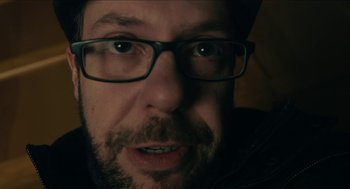 Movie still from “The Taking of Deborah Logan” (2014), directed by Adam Robitel – A person wearing glasses and a hat; Extreme Close Up shot, Low angle