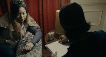 Movie still from “The Taking of Deborah Logan” (2014), directed by Adam Robitel – Two people sitting at a table writing on papers; Medium shot, Over the shoulder angle