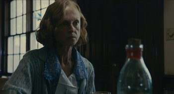 Movie still from “The Taking of Deborah Logan” (2014), directed by Adam Robitel – A woman sitting at a table with a glass of water; Close Up shot, Over the shoulder angle