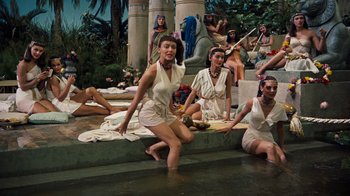 Movie still from “The Ten Commandments” (1956), directed by Cecil B. DeMille – A group of women sitting and standing around a body of water; Wide shot, High angle