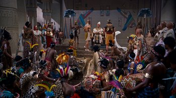 Movie still from “The Ten Commandments” (1956), directed by Cecil B. DeMille – A group of people sitting and standing around a building; Extreme Wide shot, High angle