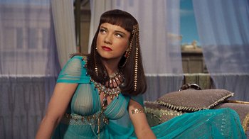 Movie still from “The Ten Commandments” (1956), directed by Cecil B. DeMille – A woman in a blue dress and a gold necklace; Medium shot, Over the shoulder angle