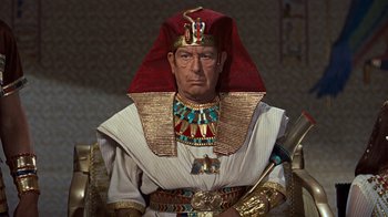 Movie still from “The Ten Commandments” (1956), directed by Cecil B. DeMille – An old man dressed as a pharaoh in a movie scene; Medium shot, High angle