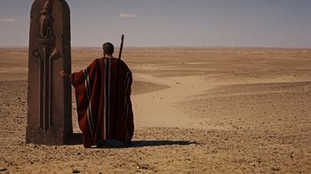 Movie still from “The Ten Commandments” (1956), directed by Cecil B. DeMille – A man in a red and black robe and a stick in his hand; Extreme Wide shot, Over the shoulder angle