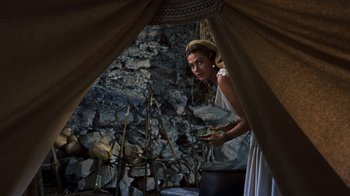 Movie still from “The Ten Commandments” (1956), directed by Cecil B. DeMille – A woman standing in front of a stone wall holding a pot; Medium shot, High angle