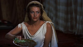 Movie still from “The Ten Commandments” (1956), directed by Cecil B. DeMille – A beautiful woman wearing a head scarf holding a plate of food; Close Up shot, Over the shoulder angle