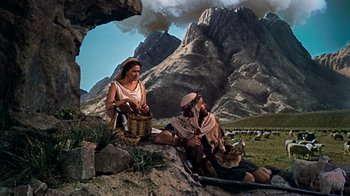 Movie still from “The Ten Commandments” (1956), directed by Cecil B. DeMille – A man and a woman sitting on a rock near a mountain; Wide shot, Low angle