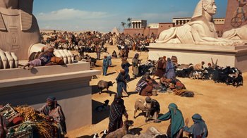 Movie still from “The Ten Commandments” (1956), directed by Cecil B. DeMille – A group of people gathered around a statue of an egyptian god; Extreme Wide shot, High angle