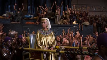 Movie still from “The Ten Commandments” (1956), directed by Cecil B. DeMille – A woman dressed in egyptian clothing standing in front of a crowd of people; Medium shot, High angle