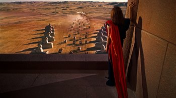 Movie still from “The Ten Commandments” (1956), directed by Cecil B. DeMille – A woman wearing a red cape looking out a window at a desert landscape; Extreme Wide shot, High angle