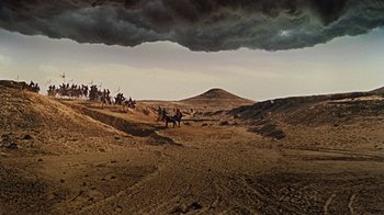 Movie still from “The Ten Commandments” (1956), directed by Cecil B. DeMille – A group of people riding horses on a dirt road; Extreme Wide shot, High angle