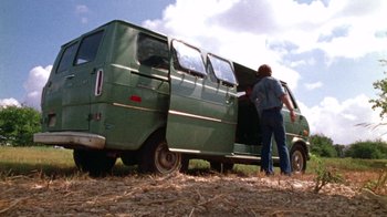Movie still from “The Texas Chain Saw Massacre” (1974), directed by Tobe Hooper – A man standing next to an old green van; Wide shot, High angle