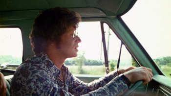 Movie still from “The Texas Chain Saw Massacre” (1974), directed by Tobe Hooper – A man driving a car in the middle of the day; Medium shot, Low angle