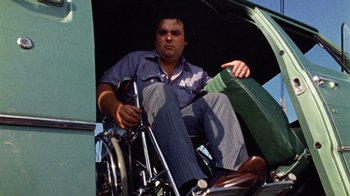 Movie still from “The Texas Chain Saw Massacre” (1974), directed by Tobe Hooper – A man sitting on a bicycle under an umbrella; Medium shot, Low angle