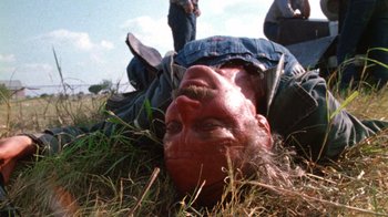 Movie still from “The Texas Chain Saw Massacre” (1974), directed by Tobe Hooper – A man laying in the grass with his head upside down; Close Up shot, Low angle