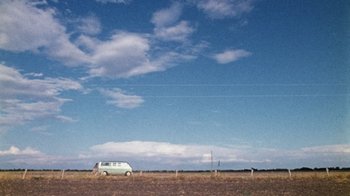 Movie still from “The Texas Chain Saw Massacre” (1974), directed by Tobe Hooper – A van parked in the middle of a grassy field; Extreme Wide shot, Low angle