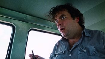 Movie still from “The Texas Chain Saw Massacre” (1974), directed by Tobe Hooper – A man holding a cell phone while sitting in a vehicle; Close Up shot, Low angle