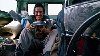Movie still from “The Texas Chain Saw Massacre” (1974), directed by Tobe Hooper – A man sitting in a bus holding a cat; Medium shot, Low angle
