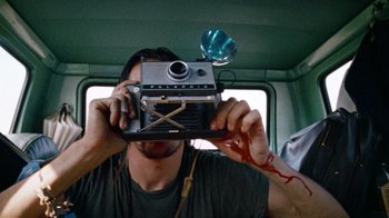 Movie still from “The Texas Chain Saw Massacre” (1974), directed by Tobe Hooper – A man taking a picture with an old fashioned camera; Close Up shot, Low angle