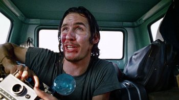 Movie still from “The Texas Chain Saw Massacre” (1974), directed by Tobe Hooper – A man sitting in the back of a car holding a mirror; Close Up shot, Low angle