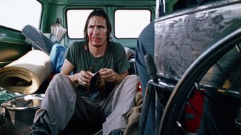 Movie still from “The Texas Chain Saw Massacre” (1974), directed by Tobe Hooper – A man sitting on the floor of a bus; Medium shot, Over the shoulder angle