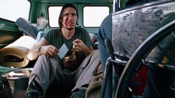 Movie still from “The Texas Chain Saw Massacre” (1974), directed by Tobe Hooper – A man sitting on a bus with a piece of paper in his hand; Medium shot, Over the shoulder angle
