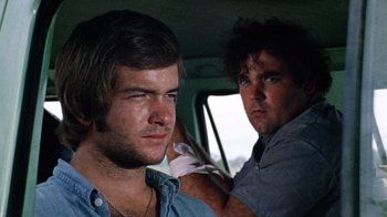 Movie still from “The Texas Chain Saw Massacre” (1974), directed by Tobe Hooper – Two men in the back seat of a car; Close Up shot, Low angle