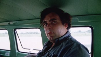Movie still from “The Texas Chain Saw Massacre” (1974), directed by Tobe Hooper – A man sitting in the driver's seat of a vehicle; Close Up shot, Low angle