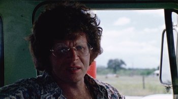Movie still from “The Texas Chain Saw Massacre” (1974), directed by Tobe Hooper – An older woman wearing glasses looking out a window; Close Up shot, Over the shoulder angle